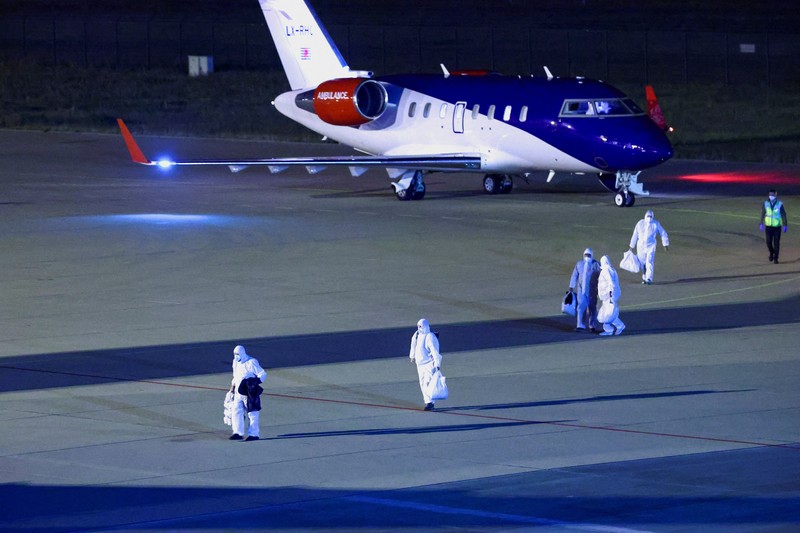 Personel berseragam hazmat berjalan di dekat pesawat yang membawa penumpang yang dievakuasi dari kapal pesiar MV Hondius, yang terkena wabah hantavirus, setelah mendarat di Pangkalan Udara Eindhoven di Eindhoven, Belanda, 12 Mei 2026. (REUTERS/Piroschka van de Wouw)