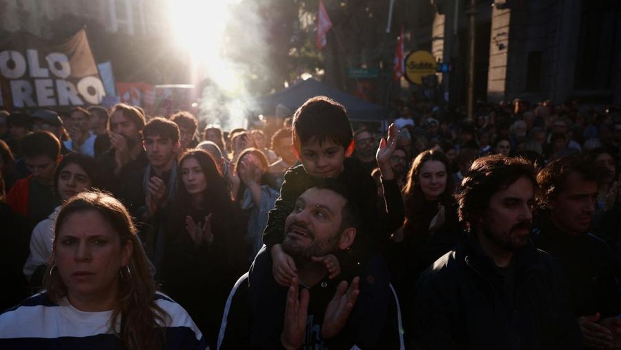 Seorang pria menggendong seorang anak saat para pekerja dan mahasiswa universitas Argentina mengikuti pawai protes menentang pemotongan dana universitas negeri, di Buenos Aires, Argentina, 12 Mei 2026.
