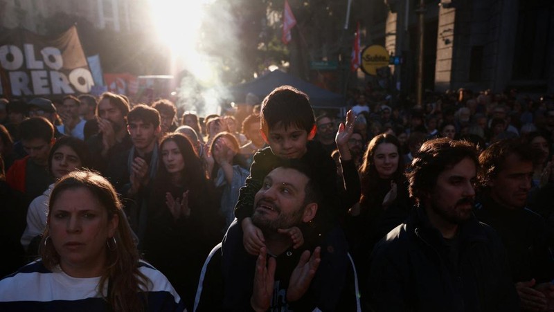 Seorang pria menggendong seorang anak saat para pekerja dan mahasiswa universitas Argentina mengikuti pawai protes menentang pemotongan dana universitas negeri, di Buenos Aires, Argentina, 12 Mei 2026.