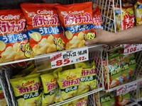 Seorang staf menambahkan stok keripik kentang Calbee ke rak di toko khusus permen di Tokyo, Jepang, 12 Mei 2026. (REUTERS/Issei Kato)