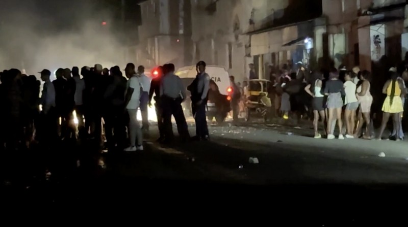 Orang-orang berjalan melewati sampah yang dibakar di tengah jalan selama protes terhadap pemadaman listrik yang sering terjadi saat Havana menghadapi pemadaman bergilir terburuk dalam beberapa dekade di tengah blokade AS yang telah mencekik pasokan bahan bakar ke pulau itu, di Havana, Kuba, 13 Mei 2026. (REUTERS/Norlys Perez)