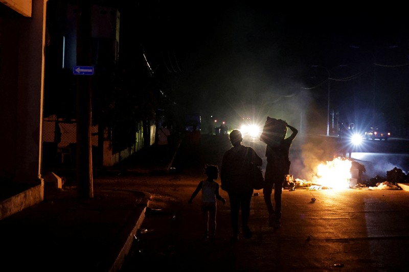 Orang-orang berjalan melewati sampah yang dibakar di tengah jalan selama protes terhadap pemadaman listrik yang sering terjadi saat Havana menghadapi pemadaman bergilir terburuk dalam beberapa dekade di tengah blokade AS yang telah mencekik pasokan bahan bakar ke pulau itu, di Havana, Kuba, 13 Mei 2026. (REUTERS/Norlys Perez)