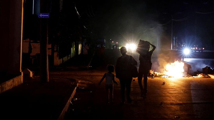 Orang-orang berjalan melewati sampah yang dibakar di tengah jalan selama protes terhadap pemadaman listrik yang sering terjadi saat Havana menghadapi pemadaman bergilir terburuk dalam beberapa dekade di tengah blokade AS yang telah mencekik pasokan b