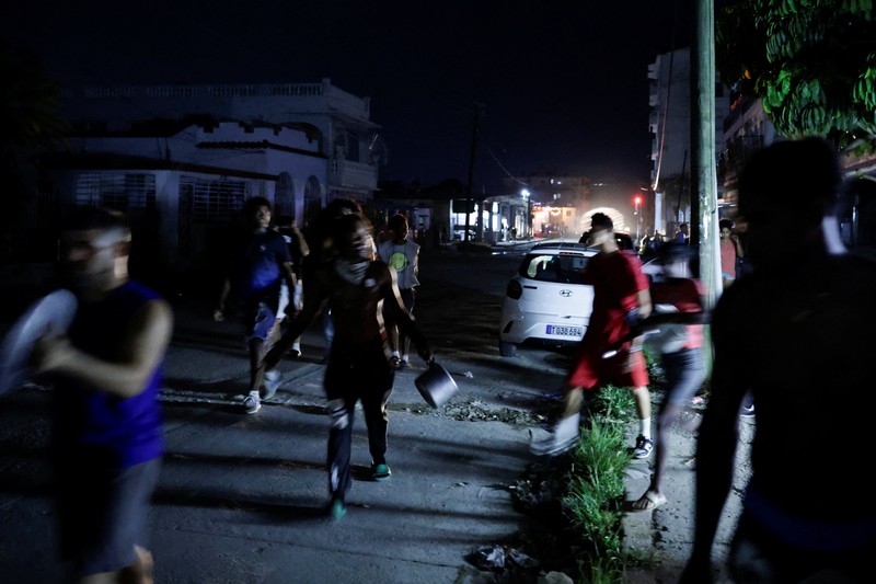 Orang-orang berjalan melewati sampah yang dibakar di tengah jalan selama protes terhadap pemadaman listrik yang sering terjadi saat Havana menghadapi pemadaman bergilir terburuk dalam beberapa dekade di tengah blokade AS yang telah mencekik pasokan bahan bakar ke pulau itu, di Havana, Kuba, 13 Mei 2026. (REUTERS/Norlys Perez)