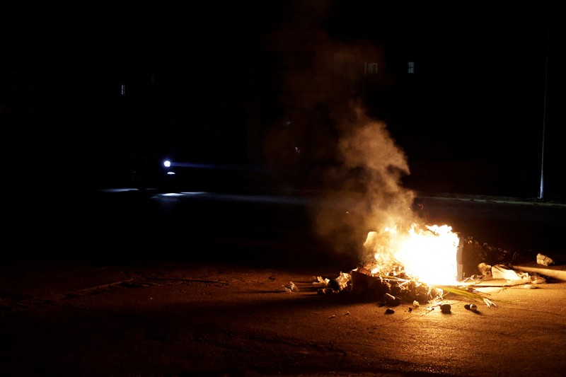 Orang-orang berjalan melewati sampah yang dibakar di tengah jalan selama protes terhadap pemadaman listrik yang sering terjadi saat Havana menghadapi pemadaman bergilir terburuk dalam beberapa dekade di tengah blokade AS yang telah mencekik pasokan bahan bakar ke pulau itu, di Havana, Kuba, 13 Mei 2026. (REUTERS/Norlys Perez)