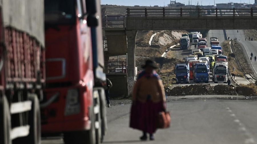 Seorang wanita berjalan di antara truk-truk yang terhenti selama berhari-hari karena para pengunjuk rasa memblokir jalan raya utama, menuntut pengunduran diri Presiden Rodrigo Paz di tengah krisis ekonomi dan bahan bakar yang sedang berlangsung, di Apacheta, Bolivia, 13 Mei 2026.
