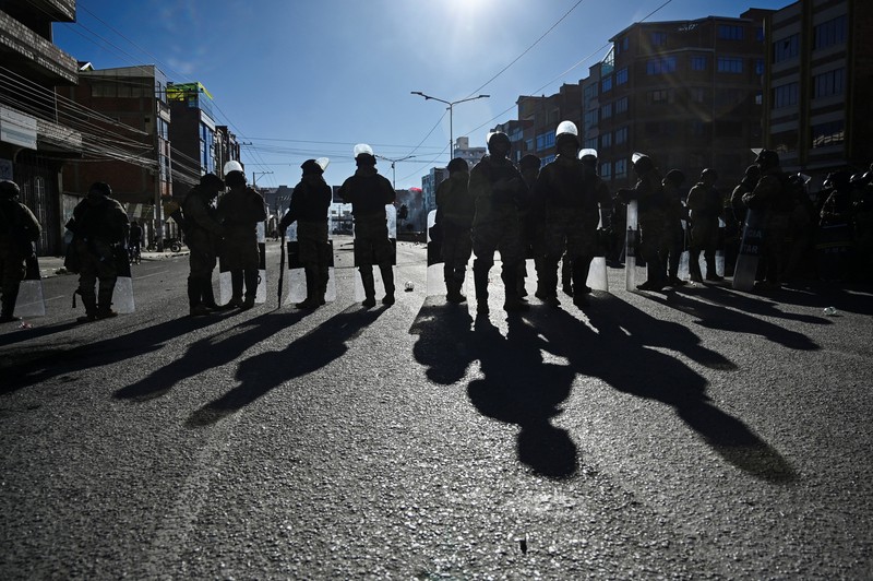 Seorang petugas polisi militer berjalan sementara seorang anak berdiri di antara bebatuan yang berserakan di jalan saat para pengunjuk rasa berdemonstrasi menentang pemerintahan Presiden Rodrigo Paz di tengah krisis ekonomi dan bahan bakar yang sedang berlangsung, di El Alto, Bolivia, 16 Mei 2026. (REUTERS/Claudia Morales)