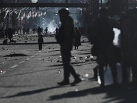 Seorang petugas polisi militer berjalan sementara seorang anak berdiri di antara bebatuan yang berserakan di jalan saat para pengunjuk rasa berdemonstrasi menentang pemerintahan Presiden Rodrigo Paz di tengah krisis ekonomi dan bahan bakar yang sedan