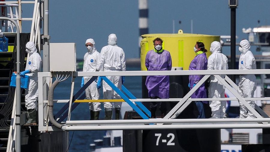 Orang-orang dengan pakaian pelindung memasuki kapal pesiar MV Hondius, yang terkena wabah hantavirus, setelah tiba di Pelabuhan Rotterdam, tempat otoritas Belanda sedang mempersiapkan pengaturan karantina, di Rotterdam, Belanda, 18 Mei 2026.