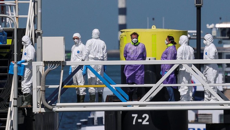 Orang-orang dengan pakaian pelindung memasuki kapal pesiar MV Hondius, yang terkena wabah hantavirus, setelah tiba di Pelabuhan Rotterdam, tempat otoritas Belanda sedang mempersiapkan pengaturan karantina, di Rotterdam, Belanda, 18 Mei 2026.