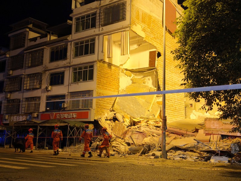 Petugas penyelamat berjalan melewati bangunan yang rusak akibat gempa bumi di desa Taiyang, Liuzhou, Daerah Otonomi Guangxi Zhuang, China, Senin (18/5/2026). (cnsphoto via REUTERS)