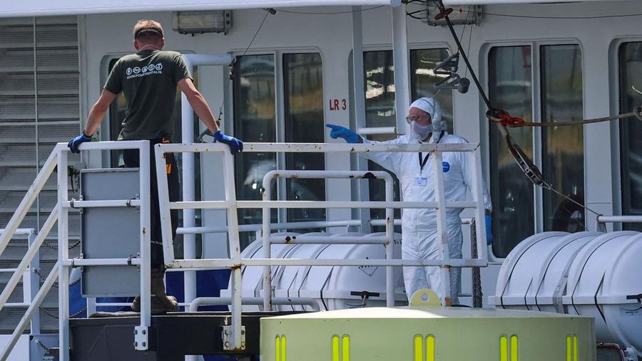 Seseorang yang mengenakan pakaian pelindung diri memberi isyarat di atas kapal pesiar MV Hondius, yang terkena wabah hantavirus, setelah tiba di Pelabuhan Rotterdam, tempat otoritas Belanda sedang mempersiapkan pengaturan karantina, di Rotterdam, Belanda, 18 Mei 2026.
