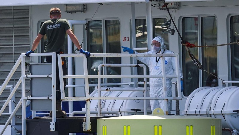 Seseorang yang mengenakan pakaian pelindung diri memberi isyarat di atas kapal pesiar MV Hondius, yang terkena wabah hantavirus, setelah tiba di Pelabuhan Rotterdam, tempat otoritas Belanda sedang mempersiapkan pengaturan karantina, di Rotterdam, Belanda, 18 Mei 2026.