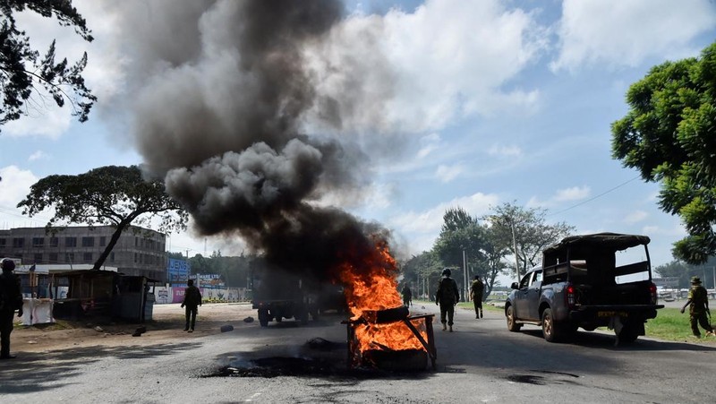 Petugas polisi anti huru hara berjalan untuk membersihkan barikade yang didirikan oleh para pengunjuk rasa selama pemogokan operator transportasi umum yang dipicu oleh kenaikan biaya bahan bakar terkait dengan tekanan pasokan global, di kota Nakuru, Lembah Rift, Kenya, 18 Mei 2026. (REUTERS/Suleiman Mbatiah)