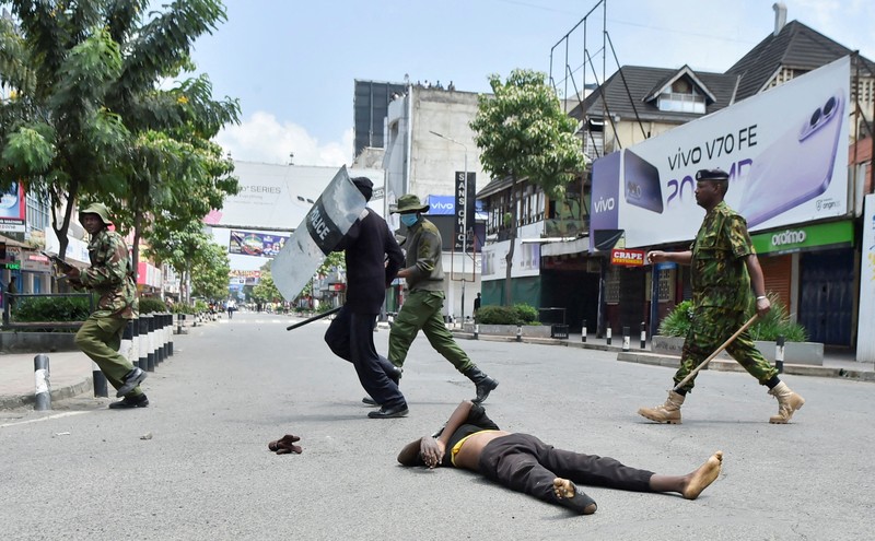 Petugas polisi anti huru hara berlari untuk membubarkan demonstran melewati mayat seorang pria yang tewas selama pemogokan operator transportasi umum yang dipicu oleh kenaikan biaya bahan bakar terkait dengan tekanan pasokan global, di kota Nakuru, Lembah Rift, Kenya, 18 Mei 2026. (REUTERS/Suleiman Mbatiah)