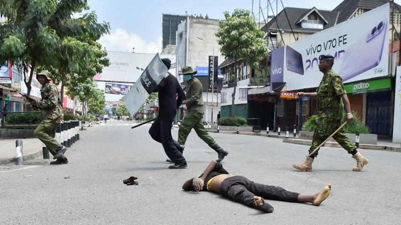 Petugas polisi anti huru hara berlari untuk membubarkan demonstran melewati mayat seorang pria yang tewas selama pemogokan operator transportasi umum yang dipicu oleh kenaikan biaya bahan bakar terkait dengan tekanan pasokan global, di kota Nakuru, Lembah Rift, Kenya, 18 Mei 2026. (REUTERS/Suleiman Mbatiah)