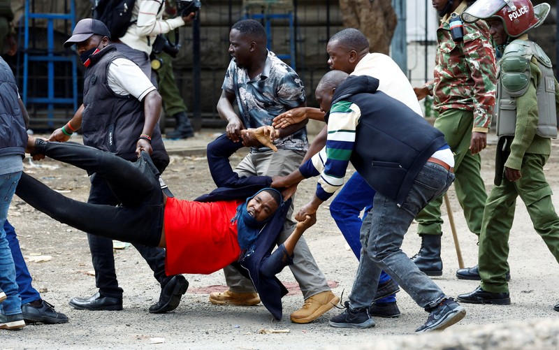 Petugas polisi anti huru hara berlari untuk membubarkan demonstran melewati mayat seorang pria yang tewas selama pemogokan operator transportasi umum yang dipicu oleh kenaikan biaya bahan bakar terkait dengan tekanan pasokan global, di kota Nakuru, Lembah Rift, Kenya, 18 Mei 2026. (REUTERS/Suleiman Mbatiah)