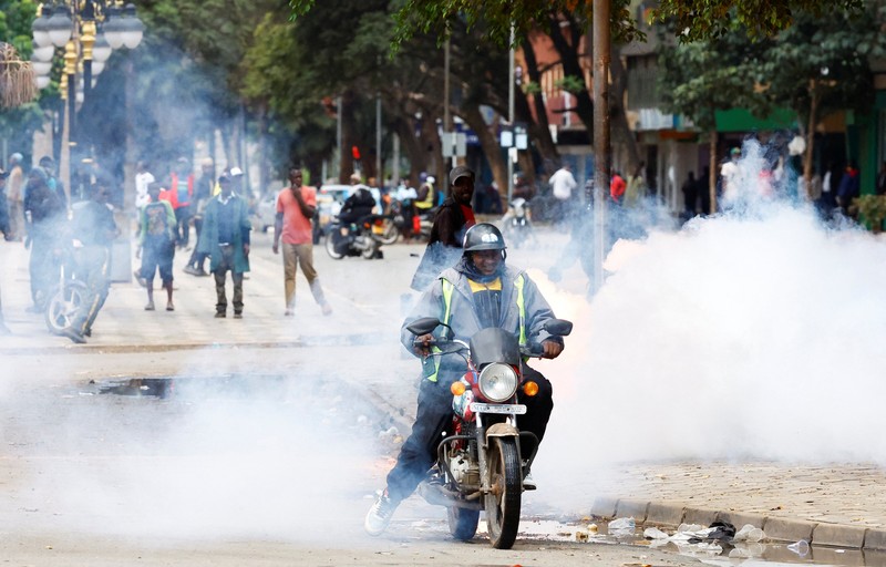 Petugas polisi anti huru hara berlari untuk membubarkan demonstran melewati mayat seorang pria yang tewas selama pemogokan operator transportasi umum yang dipicu oleh kenaikan biaya bahan bakar terkait dengan tekanan pasokan global, di kota Nakuru, Lembah Rift, Kenya, 18 Mei 2026. (REUTERS/Suleiman Mbatiah)