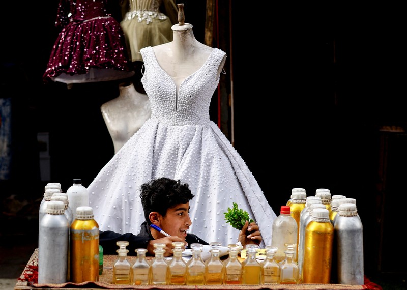 Seorang wanita Palestina melihat gaun pengantin yang dipajang di luar sebuah toko di samping tumpukan puing, saat para pengantin wanita di Gaza beralih ke gaun bekas di tengah kenaikan harga dan kekurangan yang disebabkan oleh perang, di Khan Younis di Jalur Gaza selatan, 9 Mei 2026. (REUTERS/Mahmoud Issa)