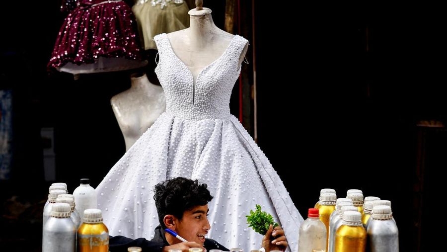 Seorang penjual parfum muda Palestina duduk di luar toko yang memajang gaun pengantin, karena para pengantin wanita di Gaza beralih ke gaun bekas di tengah kenaikan harga dan kekurangan yang disebabkan oleh perang, di Khan Younis di Jalur Gaza selatan, 9 Mei 2026.