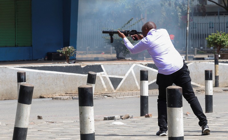 Petugas polisi anti huru hara berlari untuk membubarkan demonstran melewati mayat seorang pria yang tewas selama pemogokan operator transportasi umum yang dipicu oleh kenaikan biaya bahan bakar terkait dengan tekanan pasokan global, di kota Nakuru, Lembah Rift, Kenya, 18 Mei 2026. (REUTERS/Suleiman Mbatiah)