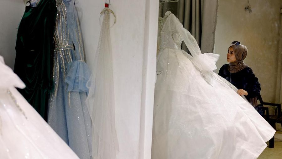 Seorang wanita Palestina melihat gaun pengantin yang dipajang di dalam sebuah toko, karena para pengantin wanita di Gaza beralih ke gaun bekas di tengah kenaikan harga dan kekurangan yang disebabkan oleh perang, di Khan Younis di Jalur Gaza selatan, 9 Mei 2026.