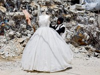 Seorang wanita Palestina melihat gaun pengantin yang dipajang di luar sebuah toko di samping tumpukan puing, saat para pengantin wanita di Gaza beralih ke gaun bekas di tengah kenaikan harga dan kekurangan yang disebabkan oleh perang, di Khan Younis