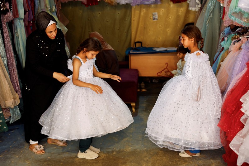 Seorang wanita Palestina melihat gaun pengantin yang dipajang di luar sebuah toko di samping tumpukan puing, saat para pengantin wanita di Gaza beralih ke gaun bekas di tengah kenaikan harga dan kekurangan yang disebabkan oleh perang, di Khan Younis di Jalur Gaza selatan, 9 Mei 2026. (REUTERS/Mahmoud Issa)