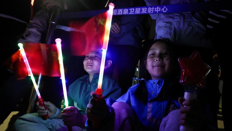 Anak-anak melambaikan bendera saat orang-orang berkumpul untuk menyaksikan peluncuran roket Long March 2F yang membawa pesawat ruang angkasa Shenzhou-23 dengan astronot Zhu Yangzhu, Zhang Zhiyuan, dan Lai Ka-ying, yang merupakan astronot pertama dari Hong Kong, ke stasiun ruang angkasa Tiangong China dari landasan peluncuran di Pusat Peluncuran Satelit Jiuquan, dekat Jiuquan, provinsi Gansu, China, 24 Mei 2026.