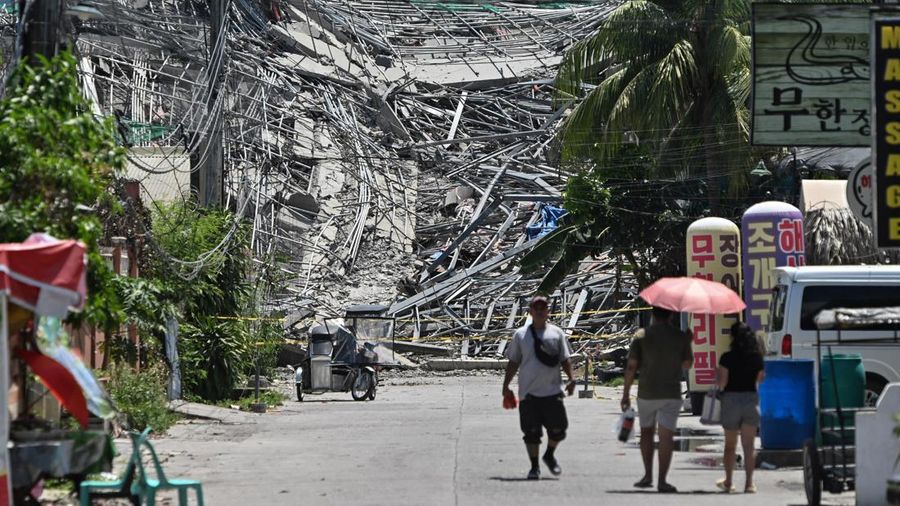 Orang-orang berjalan di dekat gedung sembilan lantai yang sedang dibangun dan runtuh di Balibago, Angeles City, Pampanga, Filipina, 24 Mei 2026.