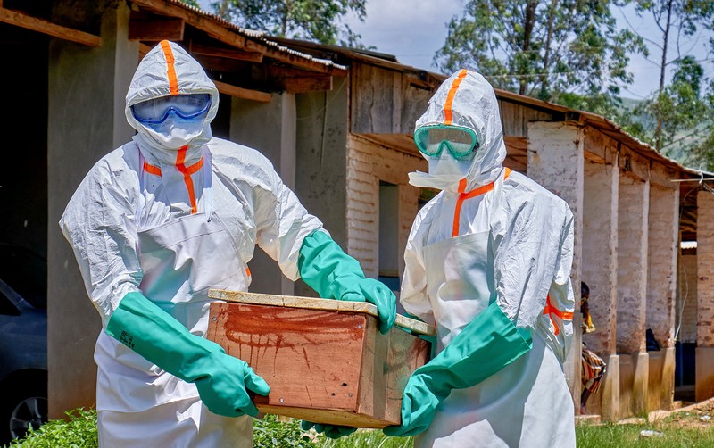 Para pekerja Palang Merah yang mengenakan alat pelindung diri (APD) berjalan dalam formasi saat mereka mendisinfeksi tanah di luar rumah seorang pria tak dikenal yang meninggal karena Ebola, sebelum mengambil jenazahnya, sementara lembaga-lembaga bantuan meningkatkan upaya untuk menahan wabah Ebola baru yang melibatkan strain Bundibugyo, di Quartier Shuni 1, sebuah sektor perumahan di Mongbwalu, Wilayah Djugu, Provinsi Ituri, Republik Demokratik Kongo, 24 Mei 2026. (REUTERS/Gradel Muyisa Mumbere)