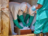 Para pekerja Palang Merah yang mengenakan alat pelindung diri (APD) menempatkan jenazah seorang anak yang meninggal karena Ebola ke dalam peti mati, sementara lembaga-lembaga bantuan meningkatkan upaya untuk menahan wabah Ebola baru yang melibatkan s
