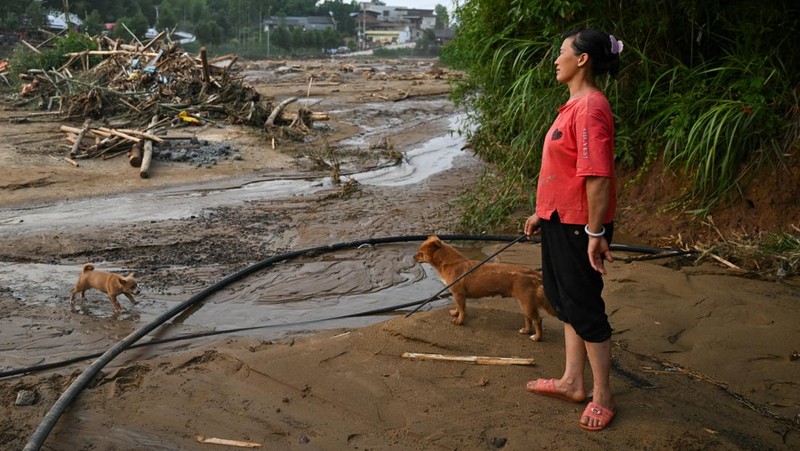Seorang warga berdiri di dekat puing-puing di desa Daqiao setelah banjir bandang dan tanah longsor yang dipicu oleh curah hujan ekstrem, di distrik Yongchuan, Chongqing, China, 24 Mei 2026.
