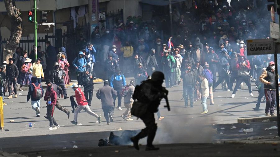 A police officer runs in front of demonstrators during a march calling for the resignation of Bolivian President Rodrigo Paz, as the country’s economic and fuel crisis worsens due to a shortage of U.S. dollars and declining domestic energy producti