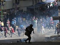 A police officer runs in front of demonstrators during a march calling for the resignation of Bolivian President Rodrigo Paz, as the country’s economic and fuel crisis worsens due to a shortage of U.S. dollars and declining domestic energy producti