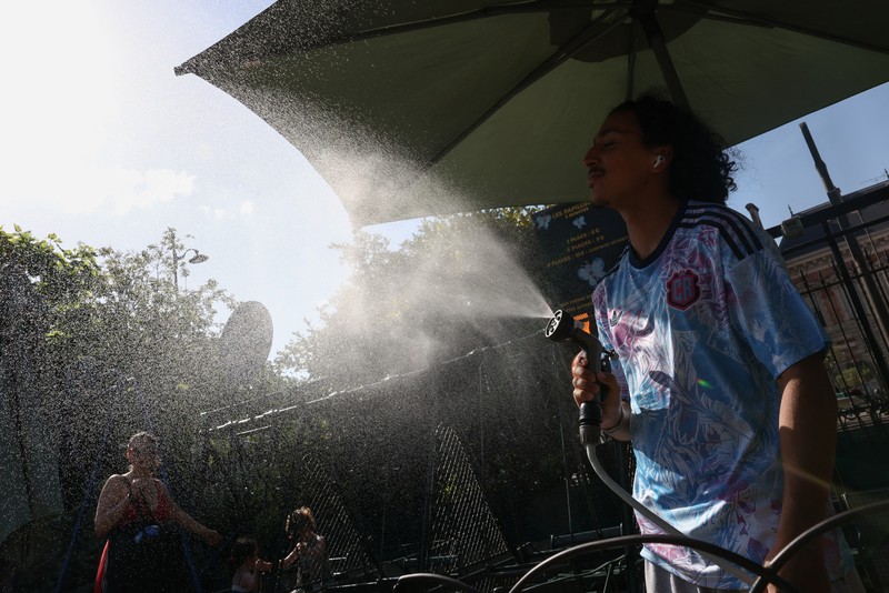A worker sprays water on people passing by in Buttes Chaumont park, as temperatures reached up to 35 degrees Celsius, during a period of hot weather in Paris, France, May 25, 2026. REUTERS/Tom Nicholson
