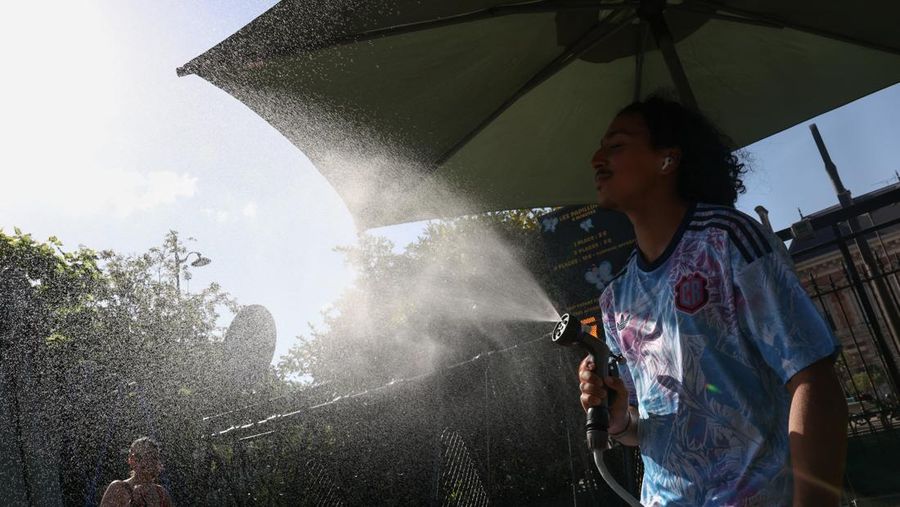 A worker sprays water on people passing by in Buttes Chaumont park, as temperatures reached up to 35 degrees Celsius, during a period of hot weather in Paris, France, May 25, 2026. REUTERS/Tom Nicholson