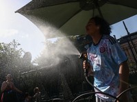 A worker sprays water on people passing by in Buttes Chaumont park, as temperatures reached up to 35 degrees Celsius, during a period of hot weather in Paris, France, May 25, 2026. REUTERS/Tom Nicholson