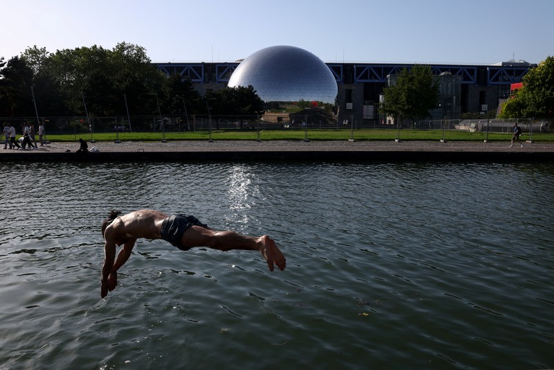 A worker sprays water on people passing by in Buttes Chaumont park, as temperatures reached up to 35 degrees Celsius, during a period of hot weather in Paris, France, May 25, 2026. REUTERS/Tom Nicholson