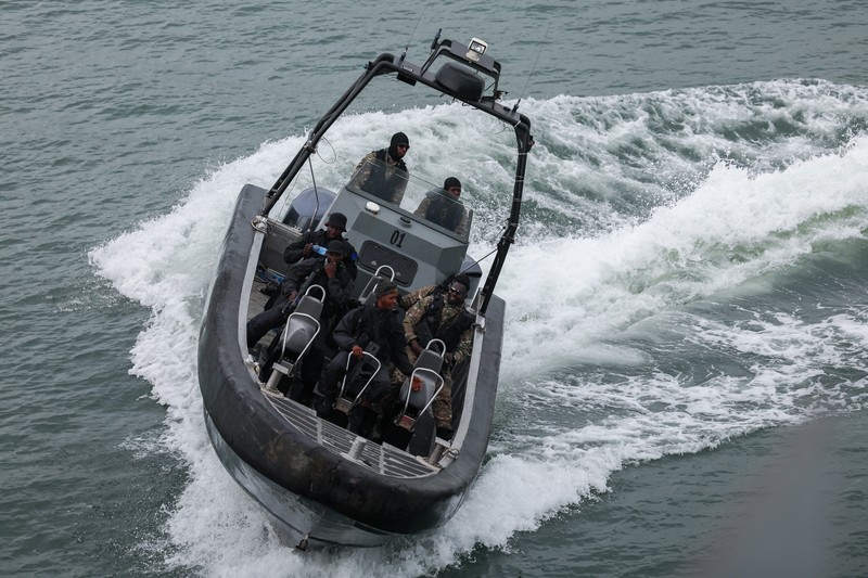 Para tamu menyaksikan anggota Unit Penerbangan Angkatan Laut Nigeria dan Layanan Perahu Khusus melakukan latihan di samping NNS Kada, kapal operasional terbesar angkatan laut, selama latihan di luar pelabuhan yang menandai peringatan 70 tahun angkatan laut di sepanjang garis pantai Atlantik di Lagos, Nigeria, 25 Mei 2026. (REUTERS/Sodiq Adelakun)