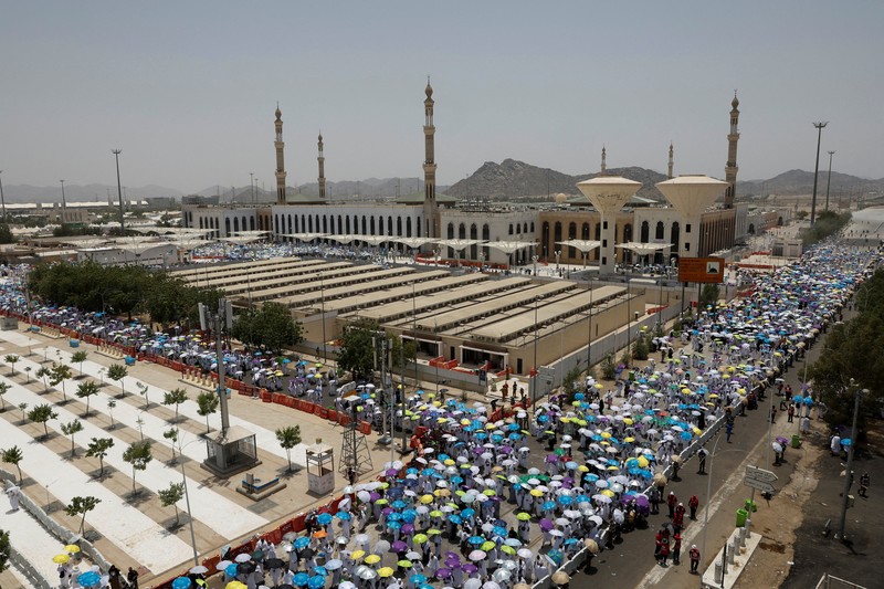Para peziarah Muslim menggunakan payung untuk melindungi diri dari terik matahari setelah salat Zuhur di luar Masjid Nimrah di Dataran Arafat selama ibadah haji tahunan, di luar kota suci Mekah, Arab Saudi, 26 Mei 2026. (REUTERS/Ibraheem Abu Mustafa)
