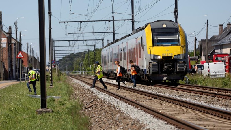 Petugas darurat berjalan di dekat lokasi kejadian di mana sebuah bus sekolah ditabrak kereta api di perlintasan sebidang yang menyebabkan banyak korban jiwa, dekat kota Buggenhout, Belgia, 26 Mei 2026.