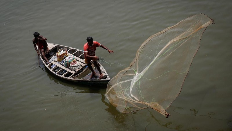 Seorang pria menebar jaring ikan ke perairan sungai Yamuna pada hari musim panas yang terik di New Delhi, India, 25 Mei 2026.