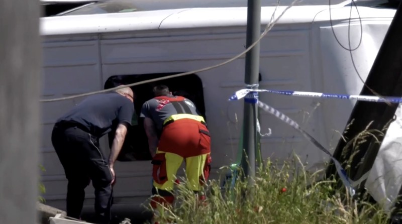 Tim penyelamat melihat bus sekolah yang rusak usai tertabrak kereta di sebuah perlintasan rel di wilayah Flanders utara, Beglia Selasa (26/5/2026) pagi waktu setempat. (Tangkapan Layar Video Reuters/)
