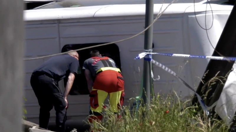 Tim penyelamat melihat bus sekolah yang rusak usai tertabrak kereta di sebuah perlintasan rel di wilayah Flanders utara, Beglia Selasa (26/5/2026) pagi waktu setempat.