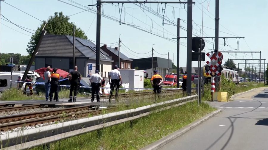 Tim penyelamat melihat bus sekolah yang rusak usai tertabrak kereta di sebuah perlintasan rel di wilayah Flanders utara, Beglia Selasa (26/5/2026) pagi waktu setempat. (Tangkapan Layar Video Reuters/)
