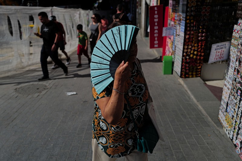 A woman with an umbrella walks at Plaza Puerta del Sol during a spring heatwave in Madrid, Spain, May 27, 2026. REUTERS/Kacper Pempel
