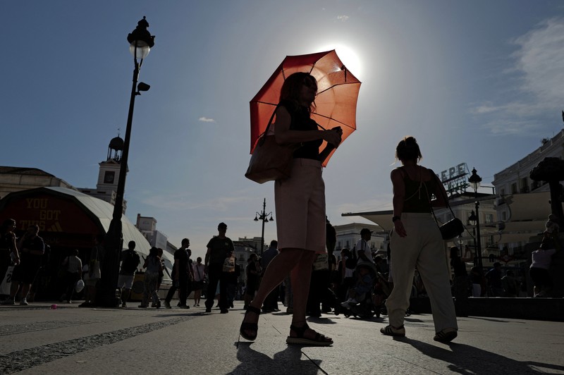 A woman with an umbrella walks at Plaza Puerta del Sol during a spring heatwave in Madrid, Spain, May 27, 2026. REUTERS/Kacper Pempel