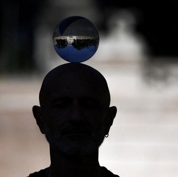 The reflection of Piazza del Popolo is seen in a crystal ball balanced on a performer’s head, in Rome, Italy, May 27, 2026. REUTERS/Yara Nardi     TPX IMAGES OF THE DAY