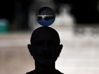 The reflection of Piazza del Popolo is seen in a crystal ball balanced on a performer’s head, in Rome, Italy, May 27, 2026. REUTERS/Yara Nardi     TPX IMAGES OF THE DAY